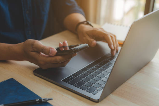 istock Businessman hand using laptop and smart phone working at home office. 1372489527