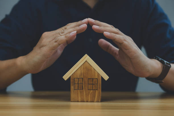 istock protecting gesture of man and house model. 1372489701