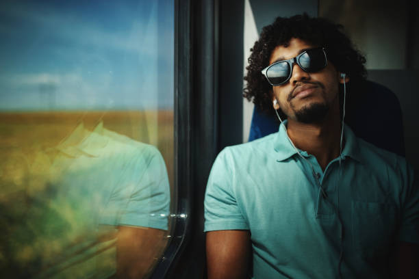 Closeup of a mid 20's African american guy listening to his music collection stored in the cell phone while taking a train ride.