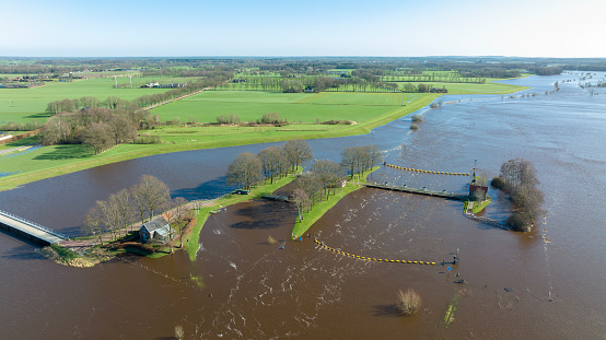 High water level in the river Vecht at the Vechterweerd weir in the Dutch Vechtdal region in Overijssel, The Netherlands. The river is overflowing on the floodplains after heavy rainfal upstream in The Netherlands and Germany during storm Eunice and Franklin in February 2022.