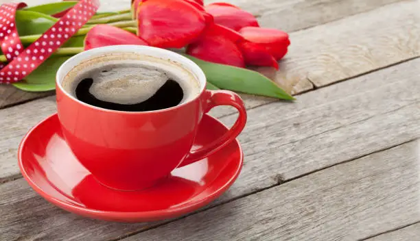 Photo of Coffee cup and red tulip flowers bouquet