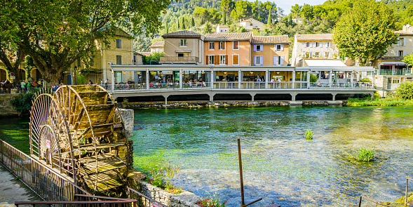 Village of Fontaine de Vaucluse and wooden paddle wheel of the Sorgue river in Provence, France