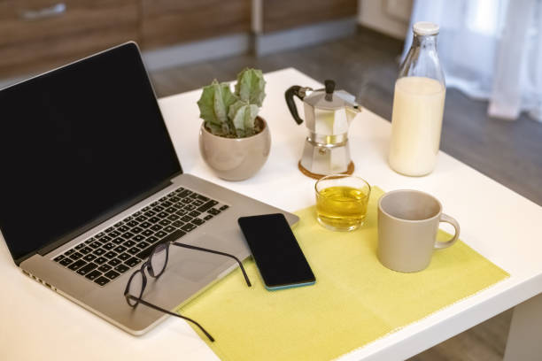 mesa para o café da manhã, cozinha ao fundo. dispositivos naturais de refeição e tecnologia. vista interior de uma casa aconchegante e moderna. millennial, juventude, trabalho em casa, educação domiciliar, conceito de trabalho remoto. - coffee pot audio - fotografias e filmes do acervo