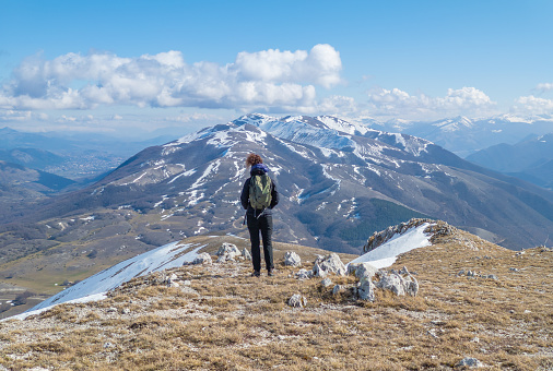 Monte Giano in Antrodoco, Italy - 20 February 2022 - A peak view of Monte Giano with snow. Summit of almost 2000 meters, Giano Mount is in province of Rieti, Lazio region, located in Apennines range. Here a view with girl hiker.