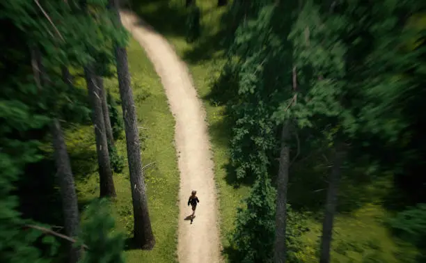 Woman with blonde hair in black top and short jeans walks on a trail in a pine forest on a sunny summers day. Aerial view. 3D render.