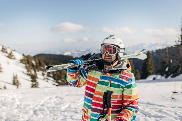 Mature man with skies standing alone on mountain on winter day.