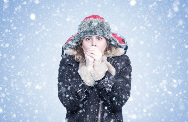 Frozen young girl in winter clothes warms her hands, cold, snow, frost, blizzard Frozen young girl in winter clothes warms her hands, cold, snow, frost, blizzard warms stock pictures, royalty-free photos & images