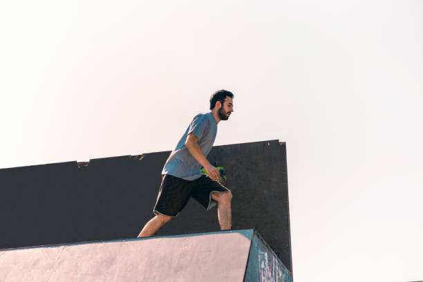 istock Sporty man training jumping over wall in skatepark 1372503713