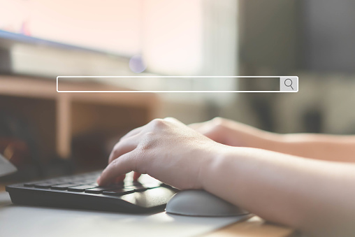 Close up of human hand typing on computer keyboard as background of search engine browser. Search browser bar without text on woman hands typing keyboard as background.