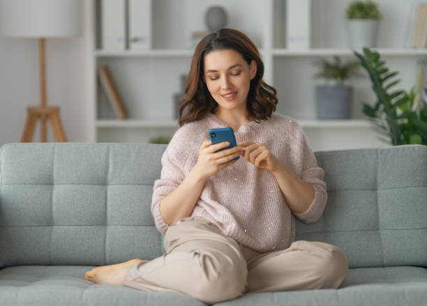 istock woman is using a phone sitting on a sofa 1372503764
