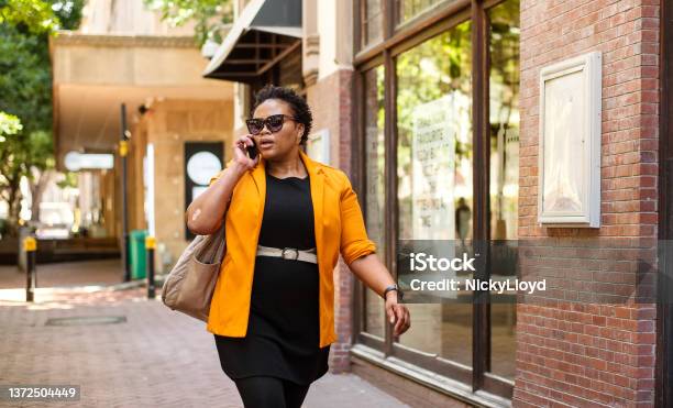 Stylish African woman talking on her phone while walking in the city