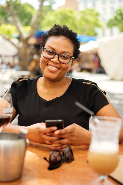 istock Smiling African woman sitting outside at a sidewalk cafe table 1372505204