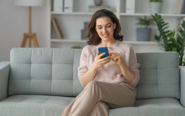 istock woman is using a phone sitting on a sofa 1372505364