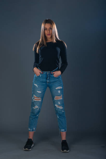 istock Beautiful young female model in jeans on dark background 1372508802