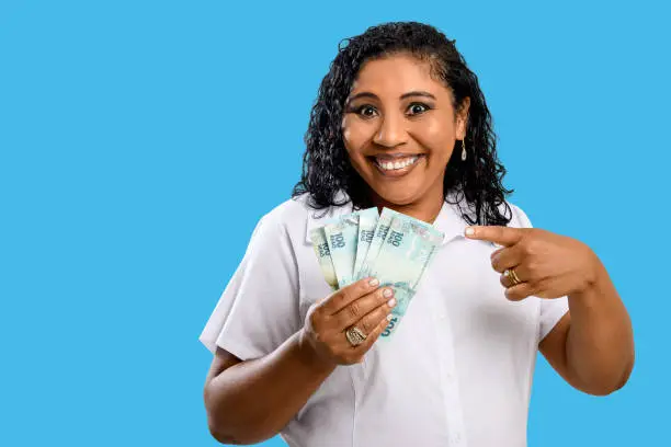 Photo of black woman smiling holding brazilian money bills, positively surprised, space for text, person, advertising concept,