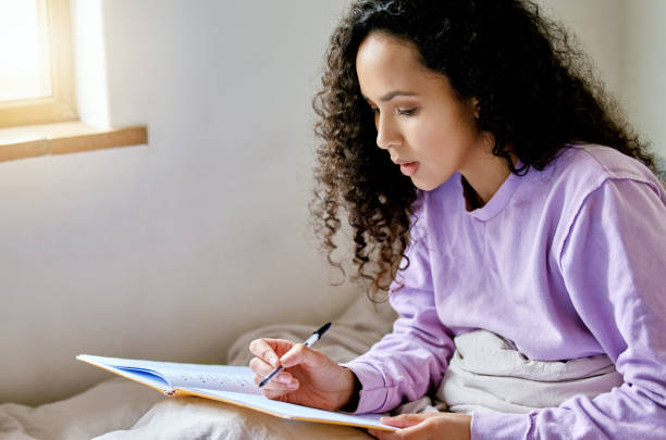 istock Shot of a young female studying while sitting in bed 1372509232