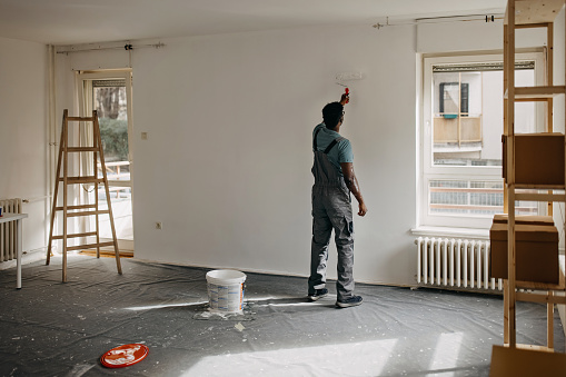 African-American professional painter paints the wall indoors