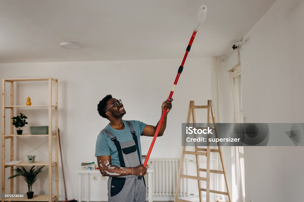 African-American professional painter paints the ceiling indoors Ceiling Stock Photo