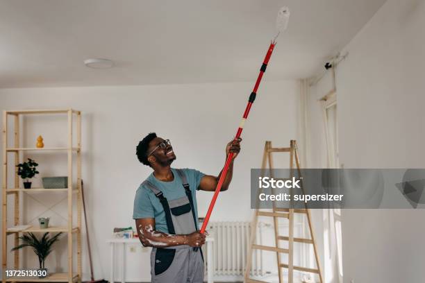 Africanamerican Professional Painter Paints The Ceiling Indoors Stock Photo - Download Image Now