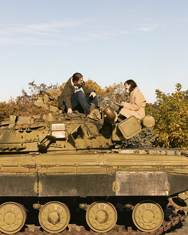 Friends chatting on top of a war tank in Kyiv