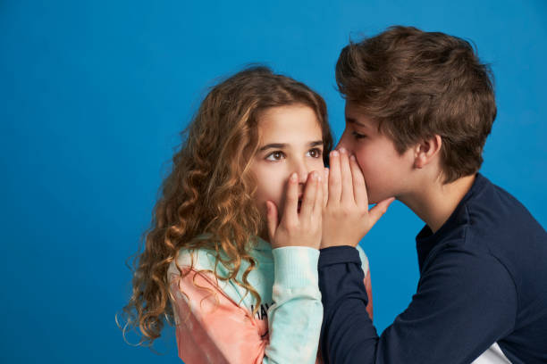 boy telling a secret and girl surprised stock photo