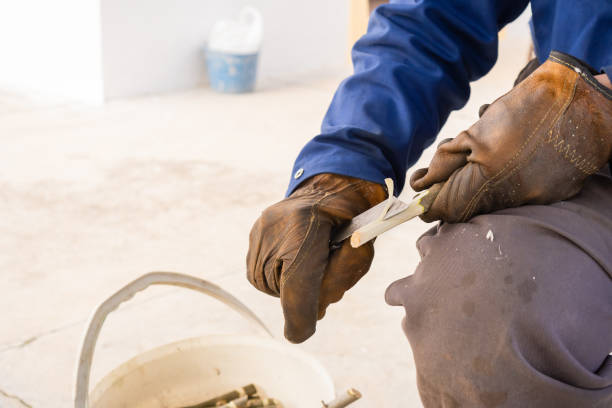 istock Person making a wood tree stake using a knife and protective gloves. Man sharpening a stick with a penknife, copy space left. 1372517154
