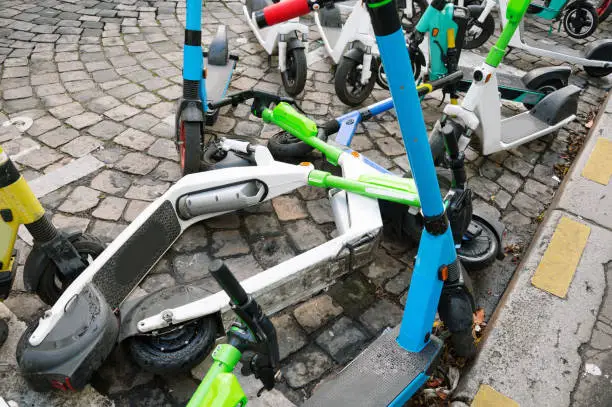 A chaotic display of electric push scooters belonging to different companies in a city street