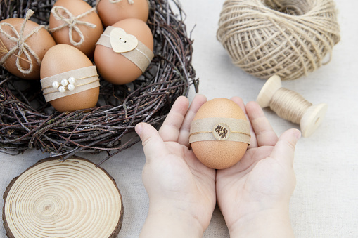 Easter eggs in nest on wite background. Easter eggs decorated with natural materials. Flat lay. Minimalistic decor for Easter. DIY