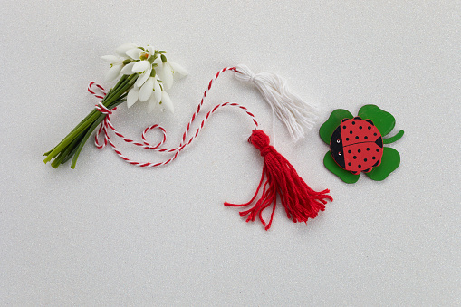 Bouquet of snowdrops on white background with red and white rope and lalybug. First of march celebration Martisor