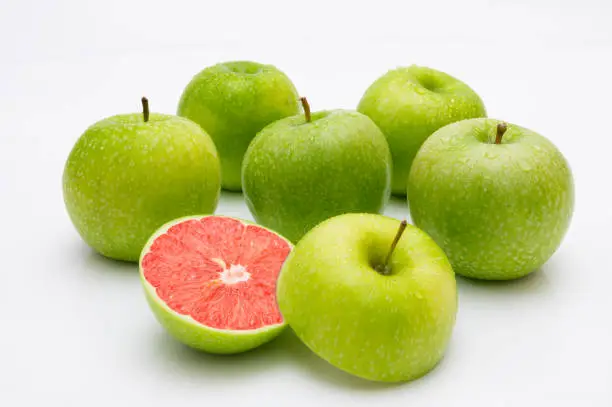 Image composition with green apples, in one there is a ripe grapefruit