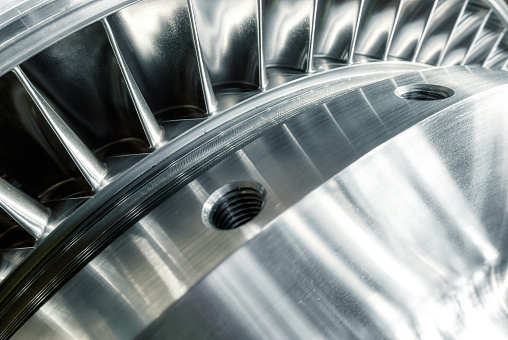 Large powerful steam turbine with shiny silver blades and holes with thread of screw in plant workshop extreme close view