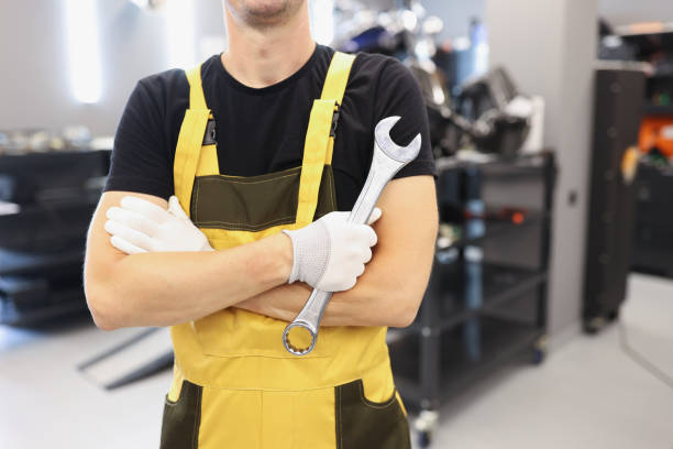 Strong man in yellow overalls holding a wrench