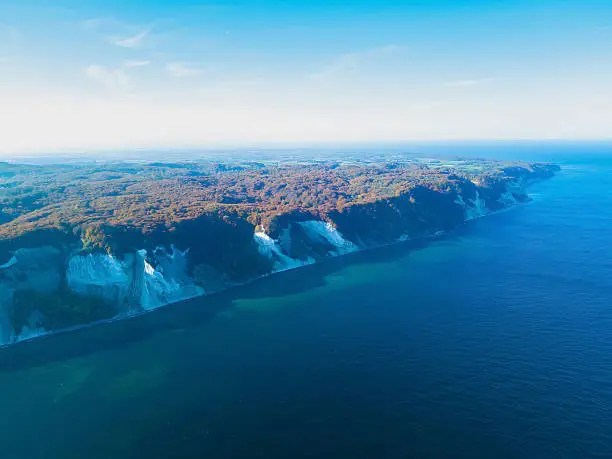 Iconic Møns Klint in Denmark on a sunny autumns day. White chalk cliffs on the Baltic coast  aerial photo.