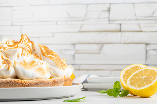 Lemon tartlets with meringue on a light background. With copy space.
