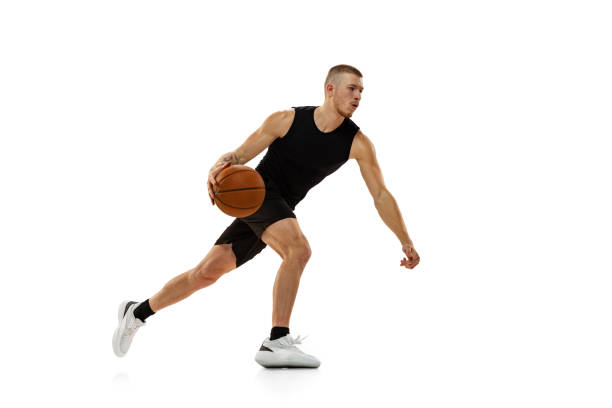 молодой мускулистый мужчина, баскетболист, тренирующийся с мячом, изолированным на белом студийном фоне. спортивные, двигательные, активны - баскетболист фотографии стоковые фото и изображения