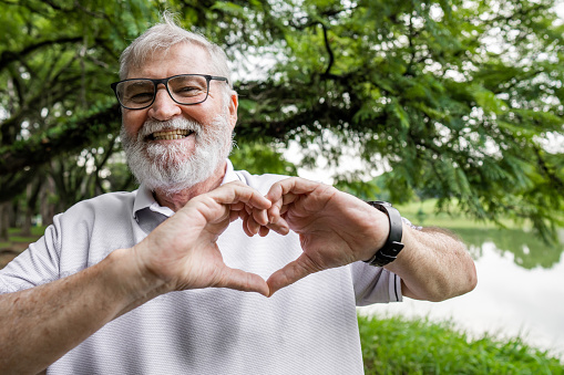A senior man making a heart symbol with his hands