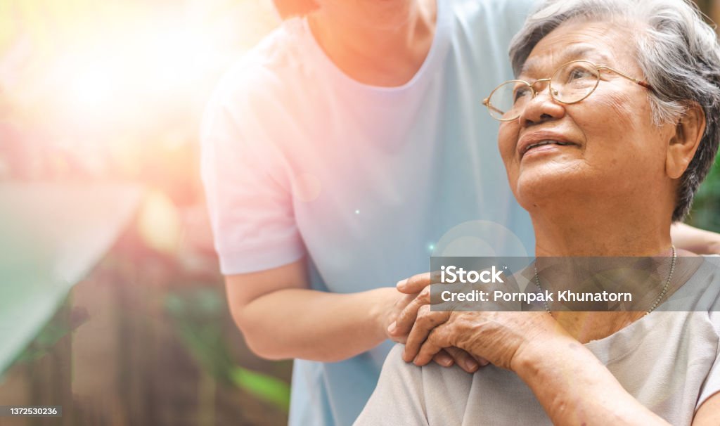 Caregiver, carer hand holding elder hand in hospice care. Philanthropy kindness to disabled concept. Senior Adult Stock Photo