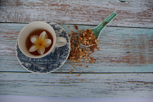 Jasmine tea, delicious and a cup with a jasmine flower, on a wooden table, top view.