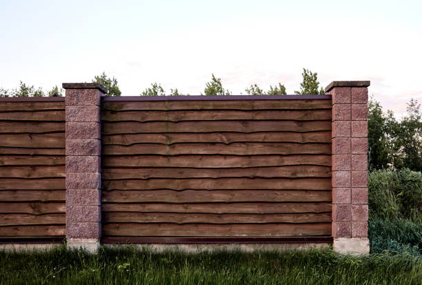 istock Brown wooden fence with block posts. Construction site. Corrugated surface. Private property fencing. Opaque hedge. Countryside backyard security exterior. Scandinavian, chalet or rustic style. DIY 1372535589