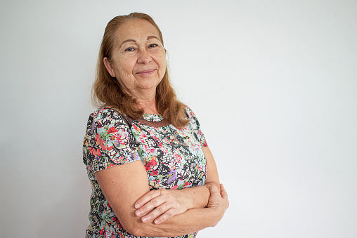 Portrait of a senior woman, gently looking at the camera, with a plain white background.