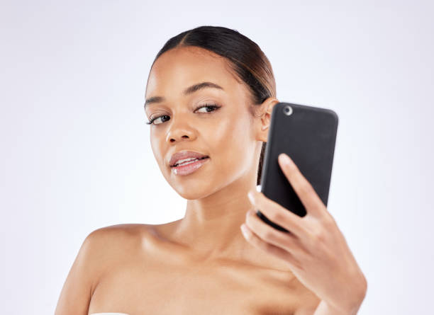 istock Shot of a young woman talking selfies using a smartphone against a studio background 1372541547