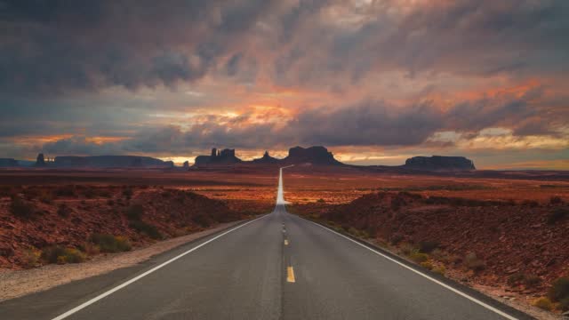 Monument Valley Navajo National Park cinemagraph seamless video loop at famous Forrest Gump running filming location highway street overlooking the red sand valley. Clouds time-lapse at the famous movie landmark in Utah, Arizona, America USA.