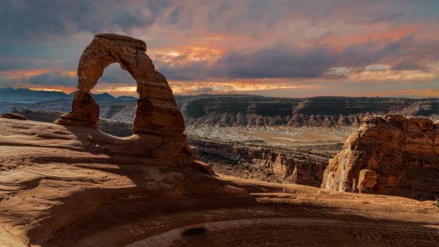 Scenic and cinematic dark thunderstorm clouds time-lapse at the famous Delicate Arch rock among the Arches National Park hiking landmarks in Utah, Arizona, America USA. Cinemagraph seamless video.