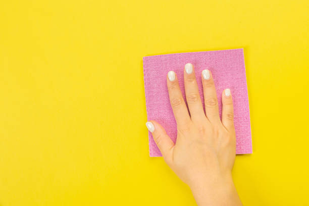 istock A housewife's hand holds a rag for dusting or washing. Empty space for text or logo on a yellow background. Early spring or regular cleaning. Cleaning and cleaning concept. 1372550012