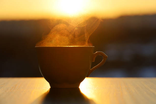 istock Hot coffee or tea cup with smoke on sunset background 1372551601