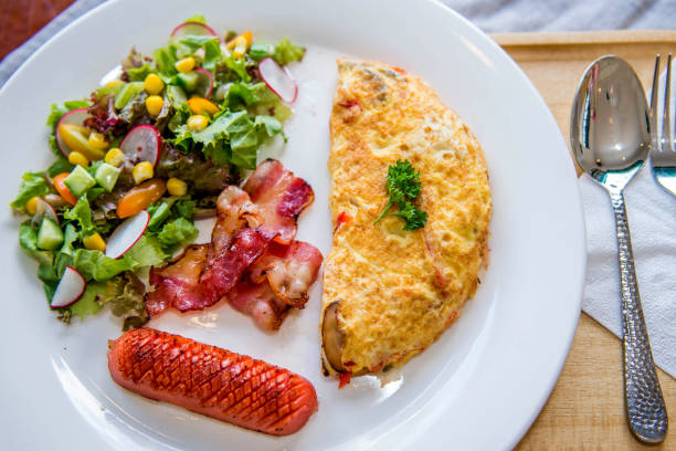 England breakfast dish with omelet, sausage, bacon and salad