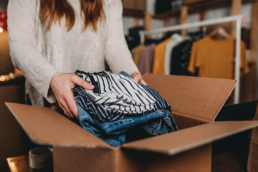 Una mujer millennial prepara el envío de algunas prendas en su nueva tienda online photo