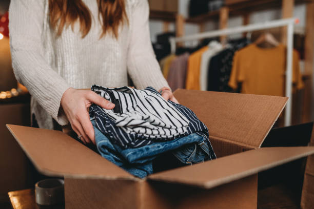 A millennial woman is preparing the shipment of some clothes in her new online shop A millennial woman is preparing the shipment of some clothes in her new online shop. She's the owner of an online thrift store. New small business concept. clothing stock pictures, royalty-free photos & images