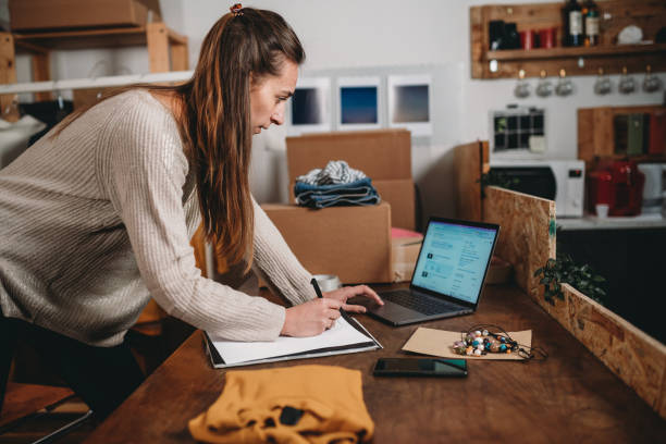 istock A young woman is checking her laptop and writing on her notebook 1372559888