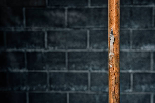 A grungy looking frozen copper pipe in a basement stock photo